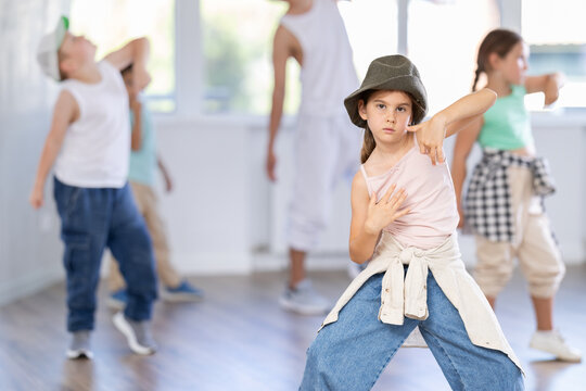 Portrait of confident tween girl hip hop dancer training during group dance class in modern dance studio