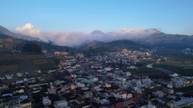 Aerial view of Bukit Skoter overlooking the town of Kecamatan Batur with rolling hills and agricultural fields in the background in Kecamatan Batur, Jawa Tengah, Indonesia.