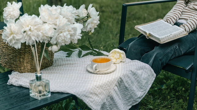 Enjoying a peaceful moment with tea and flowers while reading a book outdoors