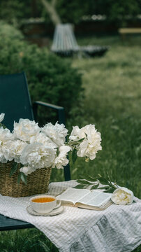 Relaxing garden moment with tea, book, and fresh peonies on a summer day