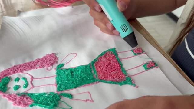 a child's hands skillfully using a turquoise 3D printing pen to create art on a sheet of white paper. Creative and educational hobby