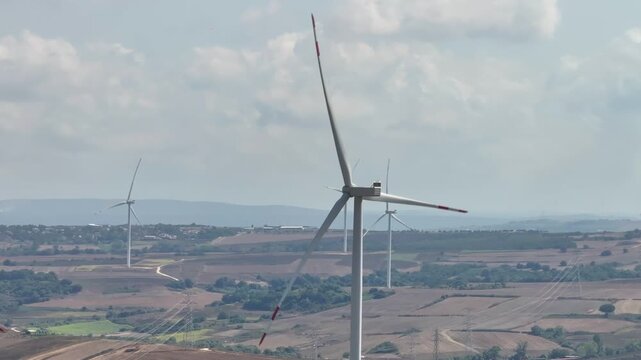 Aerial view of wind turbines spinning in a rural landscape with rolling hills and fields in Danamandira, Istanbul, Turkey.