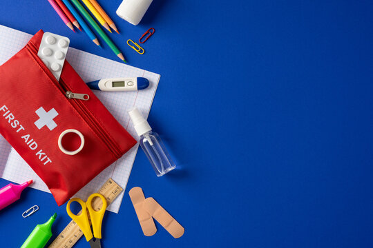 First aid kit and school supplies arranged on blue background for student health and safety preparedness