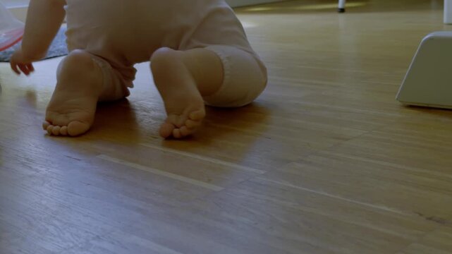 Close-up of baby feet crawling across a hardwood floor.