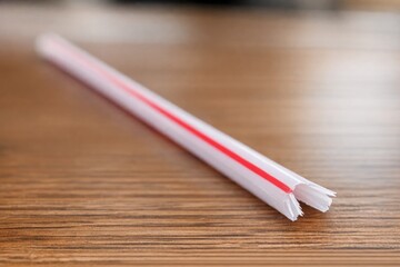 Obraz premium A single red and white straw sits on a wooden table