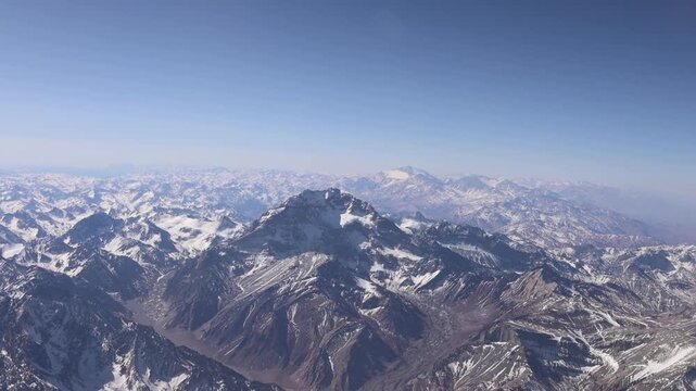 Aerial view of the snow-capped peaks of Aconcagua mountain range under a clear blue sky in Las Heras Department, Mendoza Province, Argentina.