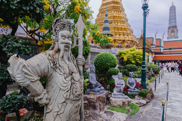 BANGKOK, THAILAND – A stone guardian statue stands guard at the Grand Palace, a popular tourist destination in Bangkok, showcasing intricate architecture. © Zenstratus