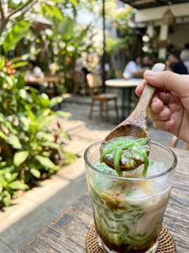 Hand holding spoon scooping cendol dessert