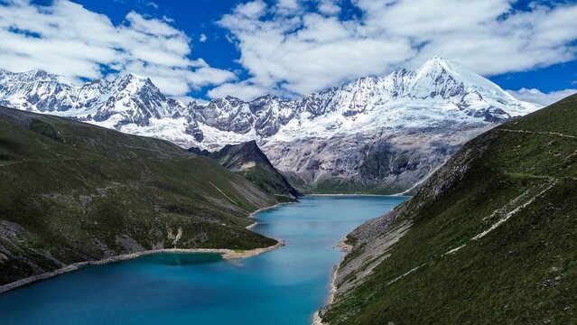 Aerial drone view of turquoise Pemahling Lake beneath snow-capped Kula Khangri peaks, Tibetan Himalayas, Lhoka Shannan, Tibet, China