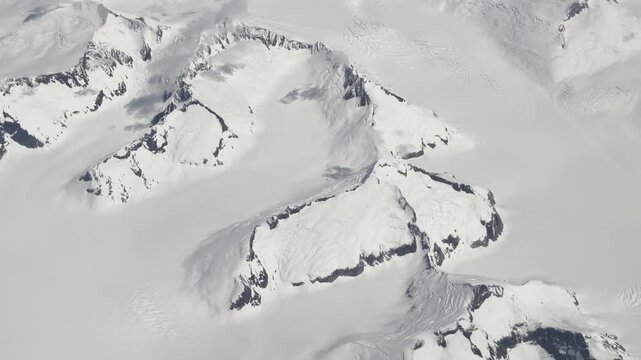 Sharp aretes and glacier channels rise from a vast white ice cap