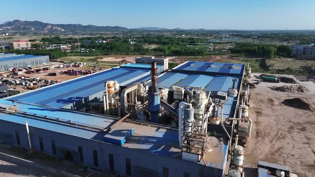 Aerial view of a chemical plant with blue roofs industrial facilities and surrounding landscape