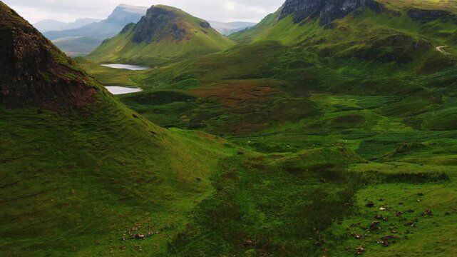 Aerial view of green rolling hills and small mountain lakes in the rugged landscape of Skye in Highland Council, Scotland, United Kingdom.