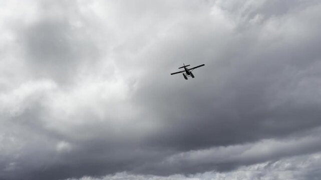 Floatplane drops low over a wide tidal estuary under grey overcast