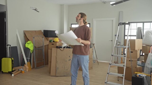 Man holding large blueprint with both hands, reading plans inside a building under renovation; project planning focused.