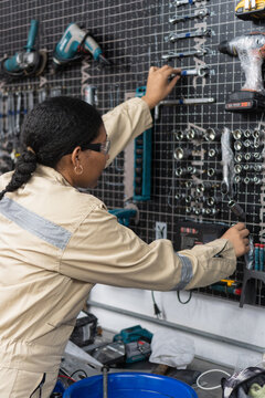Female mechanic organizing tools on workshop pegboard