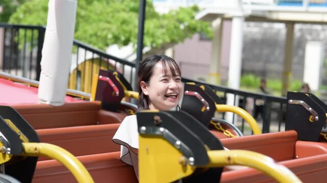 遊園地のアトラクションに乗って満面の笑みではしゃぐ若い女性と中年女性