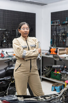Professional woman mechanic holding wrench in workshop