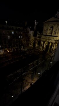 EDITORIAL USE ONLY: Vertical POV travel vlog panning from an elevated balcony showing a night view of Place de la Sorbonne and historic chapel in Paris, France.
