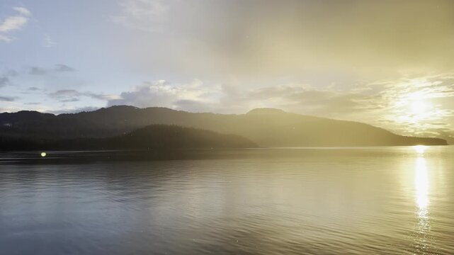 Warm hazy sun trails a path across Icy Strait dimpled by light rain