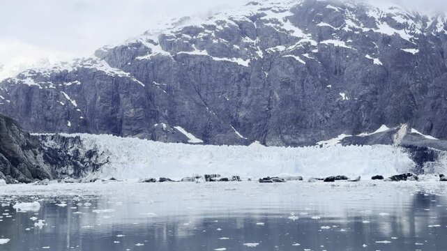 Seracs and crevasses crowd Margerie Glacier below a towering rock wall
