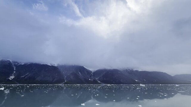 Luminous cloud spills over a dark ridge and a brash ice field