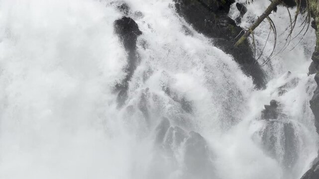 Raw whitewater shatters into mist across a knot of jagged black rock