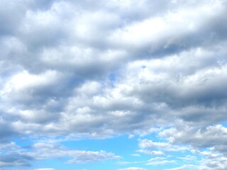 Obraz premium Dramatic gray cumulus clouds cover the blue sky, creating a textured cloudscape with natural light and changing weather conditions.