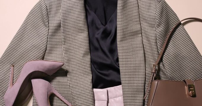 Stylish clothes, shoes and bag on beige background, top view. Camera moving up
