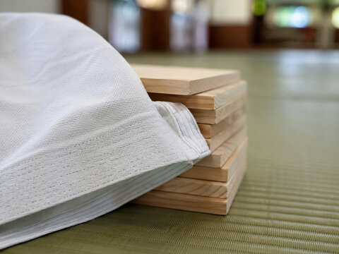 Karate gi beside stacked breaking boards on tatami, close-up martial arts training image with clean texture and dojo interior background