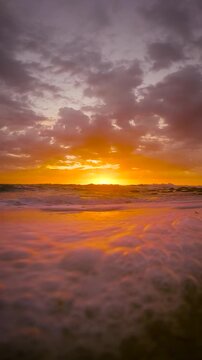 Slow motion video of gentle waves washing across the sand at sunrise as the rising sun reflects on the water at Bronte Beach, Sydney, Australia.