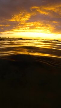 Slow motion video of a spectacular sunrise viewed from the Bogey Hole at Bronte Beach, Sydney, Australia, with calm rippling water reflecting golden morning light.