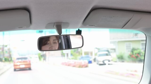 後部座席からの視点 ルームミラーに映る運転する女性と田舎道のドライブ風景