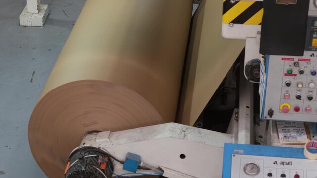 Bobina industrial de papel al final de una m&aacute;quina papelera. Producci&oacute;n de papel reciclado, manufactura, industria papelera, econom&iacute;a circular, tecnolog&iacute;a industrial