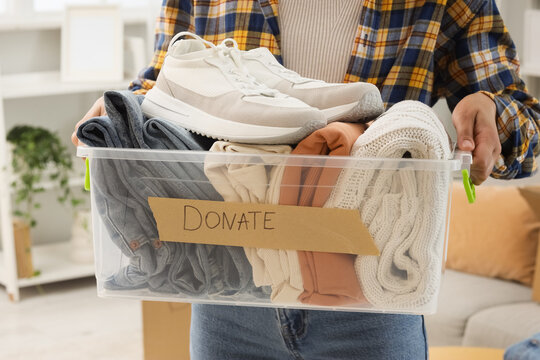 Person holding a box of clothes and shoes for donation