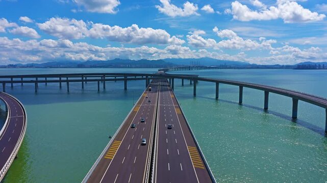 Aerial view of a delayed-motion overwater interchange: vehicles moving back and forth, the bridges scattered across the sea.Drone shot of multi-level sea interchange bridge with moving vehicles, 