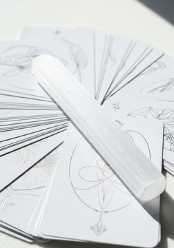 Tarot card deck with selenite crystal wand. Divination and fortune telling tool for spiritual reading. Esoteric ritual object for mystical practice, meditation and energy cleansing.