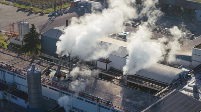 Chimeneas industriales emitiendo humo en planta fabril. Contaminaci&oacute;n ambiental, emisiones industriales, cambio clim&aacute;tico, industria, energ&iacute;a, impacto ambiental, calentamiento global