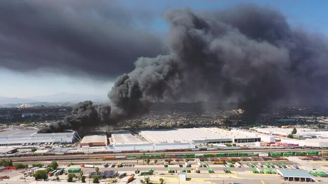 4K Drone video Warehouse fire near Boyle Heights Los Angeles CA during the day with firefighters trying to put the fire out