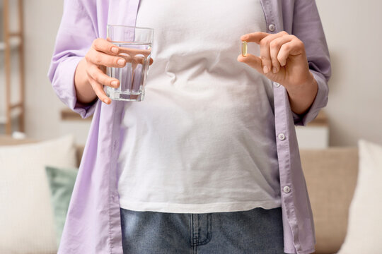 Pregnant woman with Folic acid pill and glass of water at home