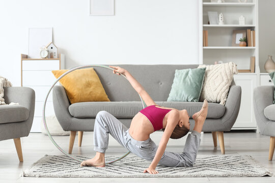 Cute girl with hula hoop doing gymnastics at home