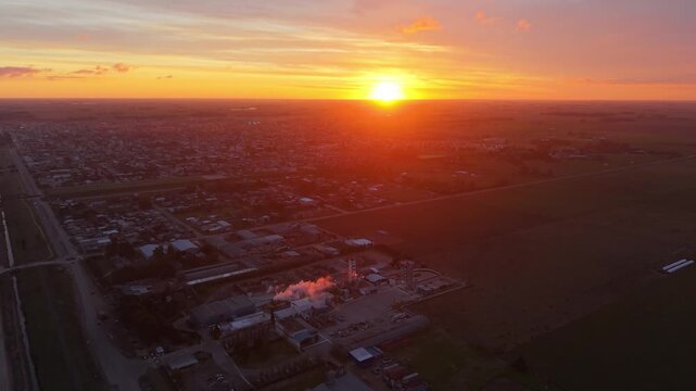 F&aacute;brica industrial con chimeneas emitiendo humo en un pueblo rural al amanecer. Industria, producci&oacute;n, energ&iacute;a, desarrollo econ&oacute;mico, trabajo, infraestructura, paisaje rural
