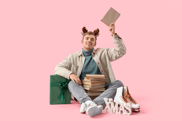 Naklejka premium Young man with many books on pink background. Christmas celebration