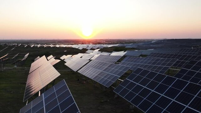 Large photovoltaic power station array landscape during sunset with solar panels aligned across open fields