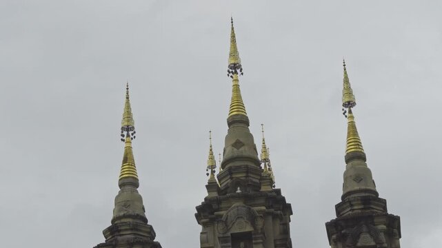 Close up of golden spires of Buddhist temple pagodas against blue sky, Thailand.