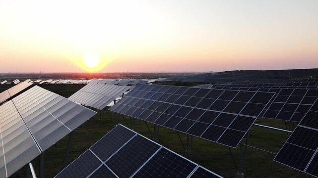 Large scale photovoltaic power station array landscape during sunset with solar panels on open fields