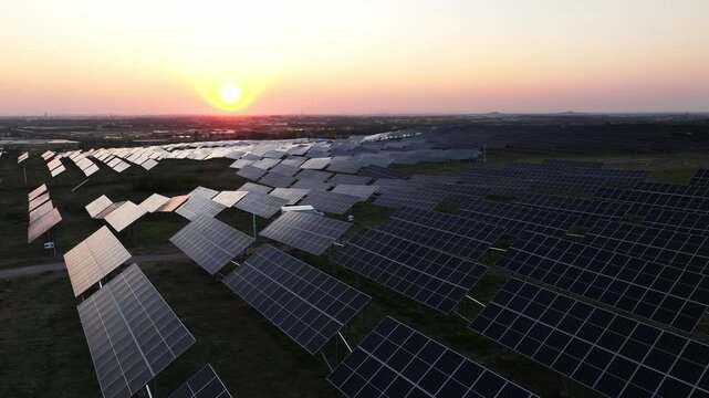 Large-scale photovoltaic power station array landscape during sunset with solar panels aligned across open fields