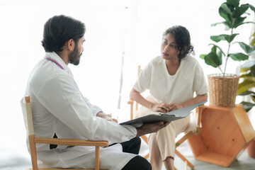 Fototapeta premium Doctor wearing a face mask examines and consults a patient during a medical checkup in a bright modern clinic.