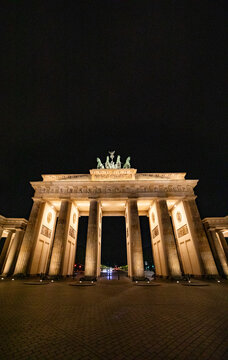 View of the illuminated Brandenburg Gate at night with its neoclassical columns and the Quadriga statue against a dark sky in Berlin, Berlin, Germany.