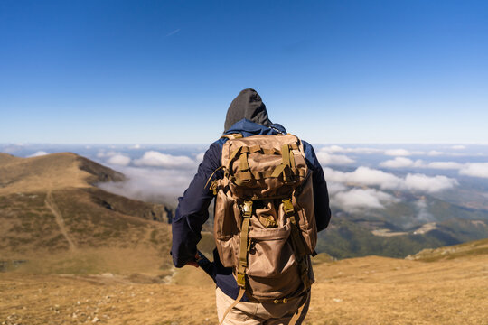 View of a hiker with a backpack standing on the grassy ridge of Botev Peak in the Balkan Mountains, Lovech, Bulgaria.