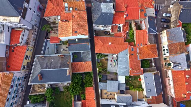 Historic residential blocks of Les Sables d'Olonne, Vend&eacute;e, Pays de la Loire, France, reveal terracotta rooftops, inner courtyards and compact urban planning, top-down slow forward drone flyover.